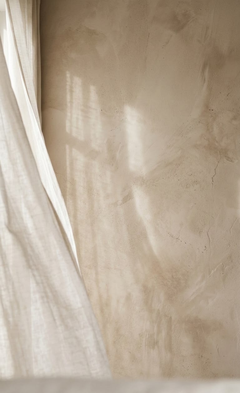 Cortina con sombras de tarde sobre una pared de yeso